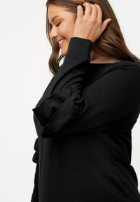 T-shirt noir à manches longues avec des accents froncés sur les manches, fabriqué dans un matériau doux, avec une coupe décontractée et un col rond.