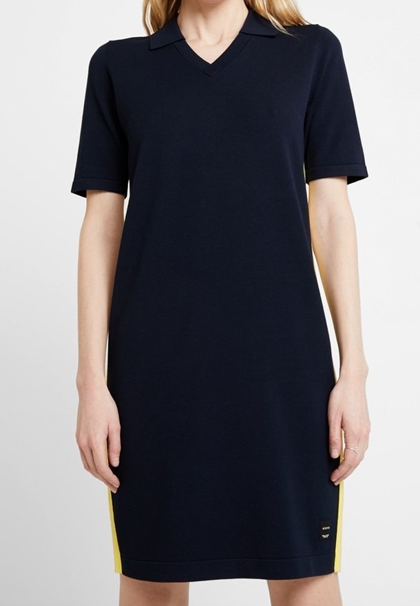 Granatowa sukienka z krótkimi rękawami, z dekoltem w kształcie litery V i żółtymi paskami po bokach. Wykonana z gładkiego, elastycznego materiału. Posiada logo w pobliżu dołu.