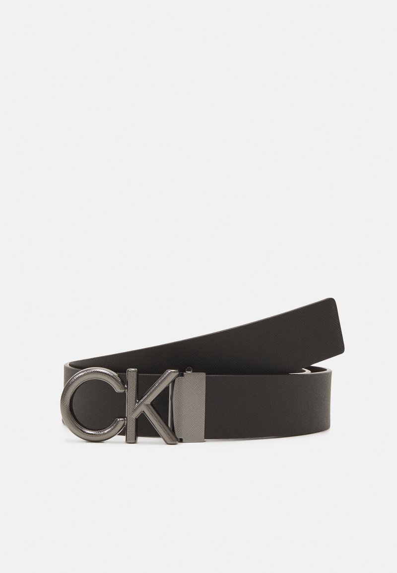 Cinturón de cuero negro con una hebilla metálica con el logo de CK. El cinturón tiene una textura suave y un diseño elegante y minimalista.