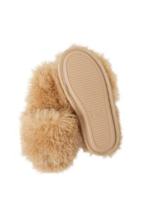 Chaussons beiges duveteux avec semelles souples, un chausson couché côté semelle vers le haut montrant le dessous rainuré et l'étiquette de taille 38/39.