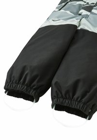 Czarne spodnie od kombinezonu zimowego z elastycznymi ściągaczami, z górną częścią w szaro-czarny wzór kamuflażu, wykonane z wodoodpornego materiału.