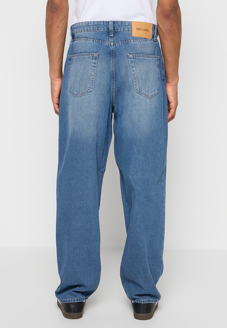 Hellblaue Jeans mit entspannter Passform, zwei Gesäßtaschen und einem braunen Markenetikett am Bund. Glatte Textur, Standardnaht.