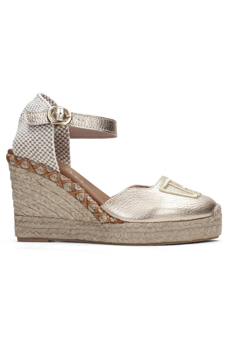 Zlaté metalické espadrilové sandály na klínku s pletenou jutovou podrážkou, kostkovaným textilním řemínkem kolem kotníku a logem na přední straně. Zapínání na přezku u kotníku.