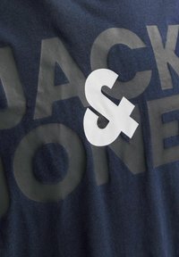 Tume sinine T-särk struktureeritud viimistlusega, millel on julge helesinine kiri ja silmatorkav valge ampersandi logo.