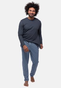 Herren-Loungewear bestehend aus einem langärmligen dunkelgrauen Oberteil und gemusterten blauen Hosen mit geometrischem Design. Weicher Stoff, lockere Passform, elastischer Bund.