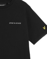 T-shirt en coton noir avec un logo blanc "LYLE & SCOTT" sur la poitrine et un emblème d'aigle brodé jaune sur la manche.