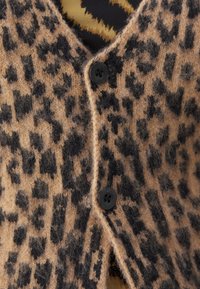 Luipaardprint cardigan in bruin en zwart, gemaakt van zachte wol, met een v-hals, twee zwarte knopen en een iets fuzzy textuur.