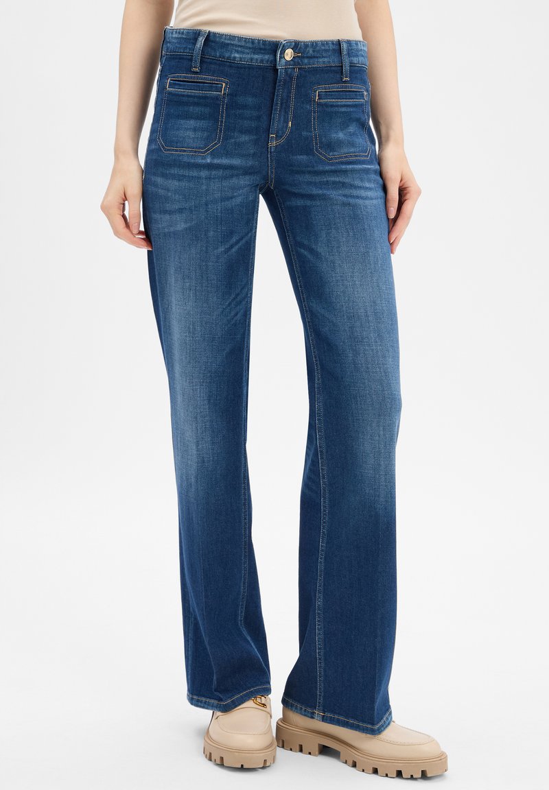 Dark blue denim jeans with a relaxed fit, featuring five pockets, topstitching details, and a button closure at the waist.