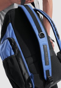 Mochila negra y azul con un respaldo de malla texturizada, correas ajustables, bolsillo lateral y una etiqueta que dice "PLANETA AGUA". Material duradero.