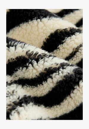 Čierny a krémový pruhovaný plyšový deka s jemnou, nadýchanou textúrou a vlnitým vzorom, ktorý obsahuje rôzne dĺžky a hĺbky látky.