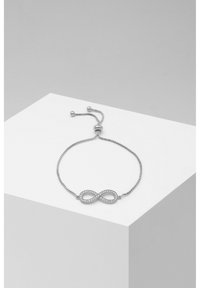 Bracelet en chaîne argentée présentant un symbole de l'infini orné de petits cristaux transparents, fermoir réglable pour un ajustement personnalisé.