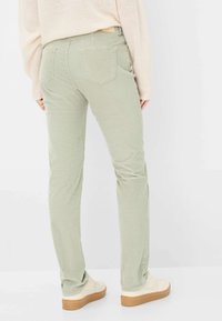 Lys grønne kordfløjl bukser med en tætsiddende pasform, der har baglommer og en glat struktur, parret med cremede sneakers.