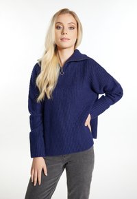 Marineblauw geribbeld sweatvest met een halve ritssluiting en lange mouwen. Zachte textuur, een ontspannen pasvorm en zijsplitsingen aan de zoom voor meer bewegingsgemak.