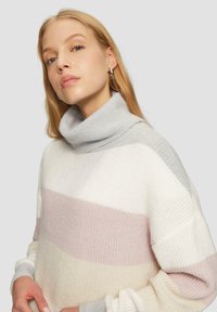 Lichte, gestreepte coltrui in wit, zachtroze en lichtgrijs. Heeft een geribbelde textuur en een ontspannen pasvorm, perfect voor het laagjes dragen.