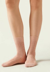 Lace-strick Knöchelsocken in sanftem Pink mit gerippten Bündchen, die ein strukturiertes Muster und eine glatte Oberfläche aufweisen, entworfen für Komfort und Atmungsaktivität.