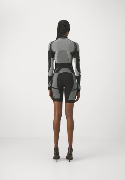 Schwarzes und graues gestricktes Set aus Cropped-Top und Shorts mit verschiedenen Strukturmustern, langen Ärmeln und einer figurnahen Silhouette. Rückansicht gezeigt.