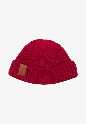 Czerwona wełniana czapka z plecionki z żebrowaną teksturą i podwiniętym brzegiem. Posiada małą prostokątną skórzaną łatkę z logo z boku.