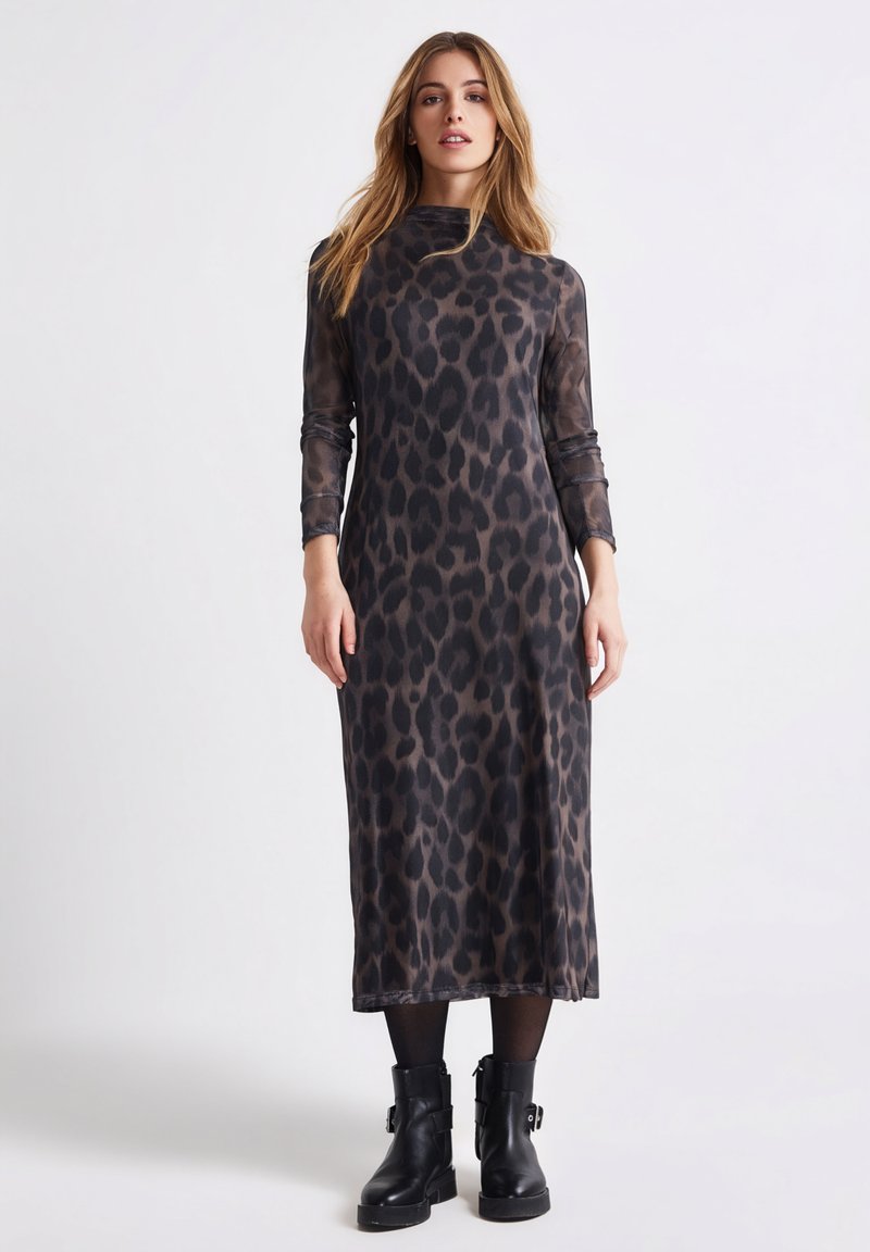 Midi sukienka w panterkę z długimi rękawami, wysokim dekoltem i dopasowanym krojem. Noszona z czarnymi botkami za kostkę, wykonana z przezroczystego materiału.