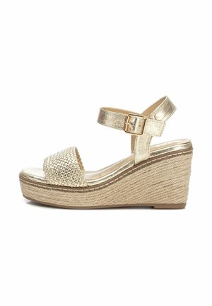 Sandalias cuña doradas con un upper metálico texturizado y plataforma de yute trenzado. Una correa en el tobillo ajustable cuenta con un detalle de hebilla.