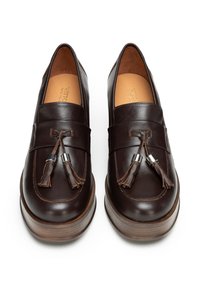 Braune Leder-Halbschuhe mit einer flachen Holzplattformsohle, die dekorative Quasten und ein genähtes Band an der Vorderseite aufweisen.