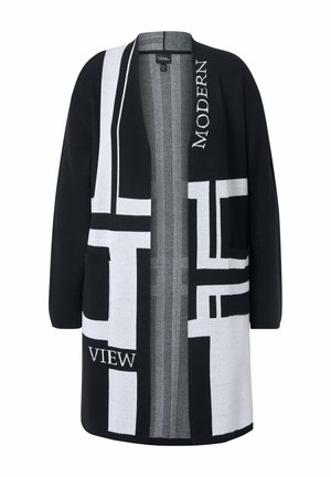 Cardigan noir et blanc avec des motifs géométriques abstraits, ouvert sur le devant, deux poches et un tissu texturé. Le texte indique "MODERNE" et "VUE."