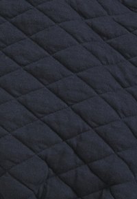 Tissu matelassé en marine foncé, présentant un motif texturé de carrés en relief, fabriqué à partir d'un matériau doux et durable avec une finition lisse.