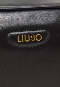 Borsa in pelle nera con dettagli cuciti e un'etichetta in oro con la scritta "LIU·JO". Texture liscia e design elegante.