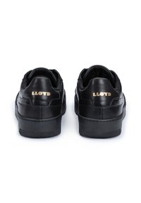 Sneakers in pelle nera con finitura testurizzata, dotati di una punta liscia e logo dorato sulla parte posteriore. Suola in gomma con design a profilo basso.