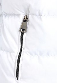 Geniale weiße Jacke mit einem schwarzen Reißverschluss und einem silbernen Zugband, das die genähten Nähte und die glatte Textur hervorhebt.