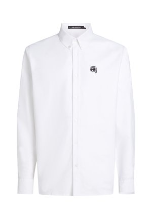 Camisa blanca de algodón tipo button-up con mangas largas, cuello con solapa y un pequeño logo negro bordado en el lado izquierdo del pecho.