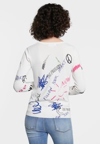 Weißer Langarmpullover mit verschiedenen bunten Grafikdesigns, darunter Texte und Formen, sowie einem gerippten Saum und Ärmeln.