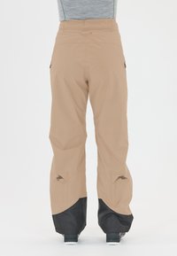 Beiga utomhusbyxor med justerbara manschetter, nätfickor och en svart nederdel. Tillverkade i lätt, vattenavvisande material.