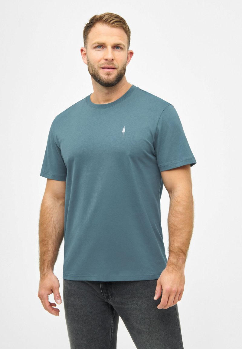 Teal katoenen T-shirt met een ronde hals en korte mouwen; heeft een klein wit boomblaadje logo op de linkerborst. Soepele textuur, casual pasvorm.