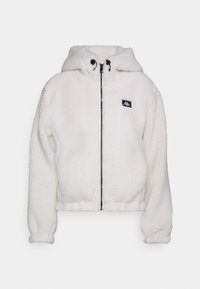 Chaqueta de forro polar blanca con cremallera, capucha, puños elásticos y un pequeño parche de logo negro en el pecho.
