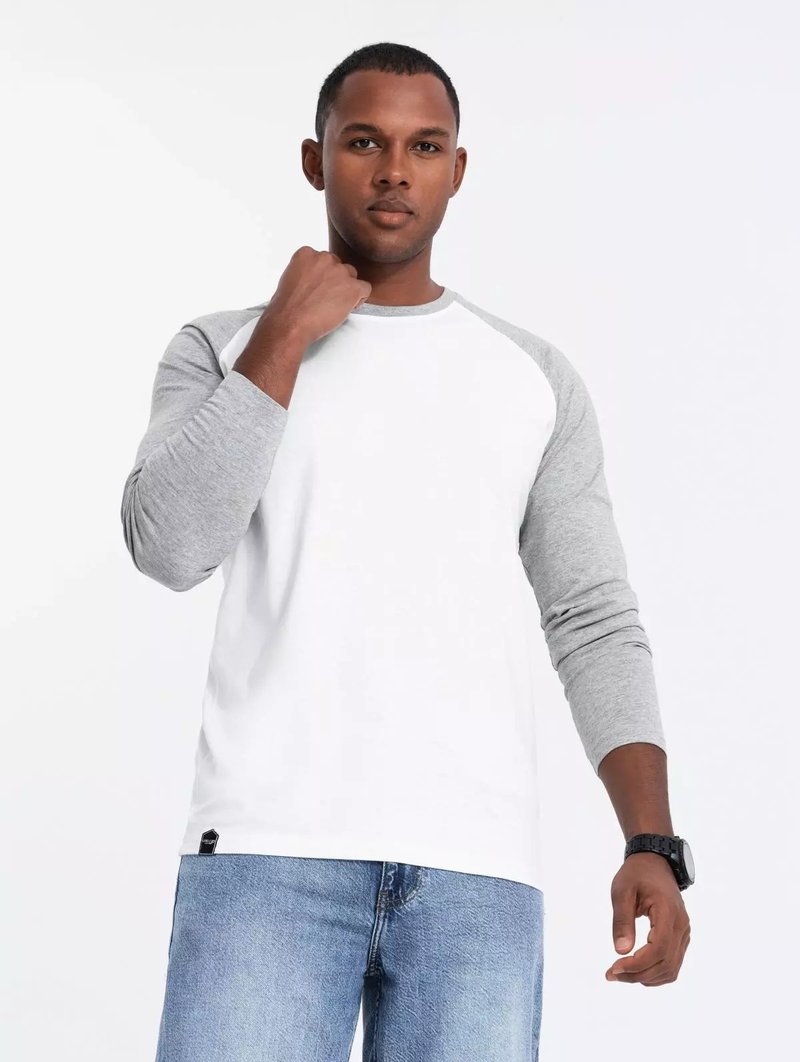 Weißes Langarmshirt mit grauen Raglanärmeln, ausgestattet mit einem Rundhalsausschnitt und einem lässigen Schnitt. Kombiniere es mit hellblauen Jeans und einer schwarzen Uhr.
