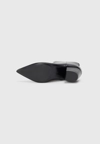 Escarpin noir à talon haut avec un bout pointu, tige en cuir lisse et une semelle à plateforme robuste. Présente un talon effilé et un minimalisme dans le design.
