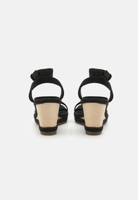 Black wedge sandals with a textured fabric upper, ankle strap, and woven jute-like heel. The heel is approximately 5 cm tall.