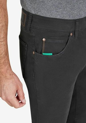 Schwarze Hose mit slim Fit, ausgestattet mit einer Vordertasche mit braunem Akzent und einem sichtbaren grünen Label, aus glattem Material.