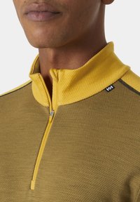Quarter-zip top met een gele kraag en rits, met een gestructureerd olijfgroen lichaam. Inclusief marineblauwe accenten en een klein logo op de schouder.