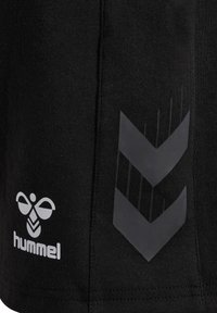 Schwarze Sportshorts aus strukturiertem Stoff mit einem weißen Logo und einem glänzenden schwarzen Chevron-Muster an der Seite.