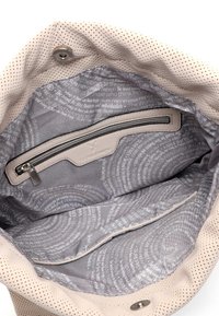 Bolso perforado de color rosa claro con un interior de tela suave que cuenta con un bolsillo con cremallera y un forro estampado. Herrajes plateados y cierre a presión.