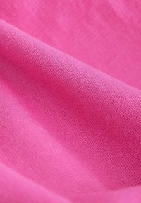 Tissu à texture douce de couleur rose vif avec un motif de tissage visible et des plis subtils à la surface.