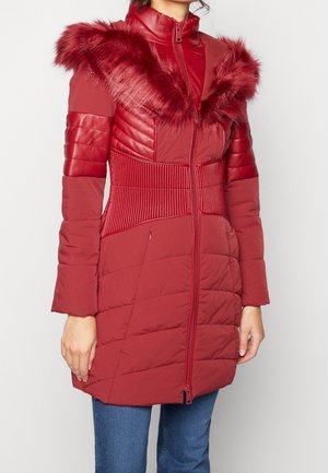 Red puffer coat with a faux fur collar, quilted texture, and ribbed side panels. Features a zip front and long sleeves.