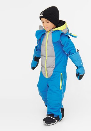 Tuta da neve imbottita blu e grigia con accenti gialli vivaci, dotata di cappuccio e elementi di design distintivi che ricordano le orecchie di un animale. Guanti neri e stivali.