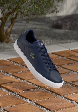 Marineblaue Sneaker aus Leder mit weißer Gummisohle, diagonalen Seitenpaneelakzenten und gesticktem Logo auf der Zunge.