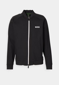Svart zip-up jacka med ståkrage, med en vit "BOSS"-logotyp, tillverkad av slätt tyg, inkluderar sidofickor och elastiska mudd.