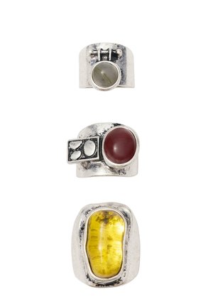 Trzy srebrne pierścienie ułożone pionowo, każdy z innym kamieniem kolorowym: jasnoszarym, ciemnoczerwonym i nieregularnie ukształtowanym żółtym bursztynem.