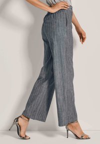 Grijze, gestreepte broeken met een relaxte pasvorm, voorzien van verticale lijnen en een hoge taille, gecombineerd met zwarte hoge hakken sandalen.