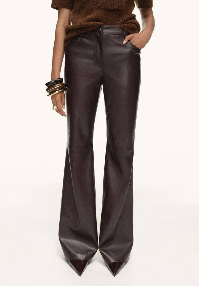 Brown faux leather flared pants with a smooth texture, high waist, side pockets, and a slight sheen. Accented with pointed toe shoes.