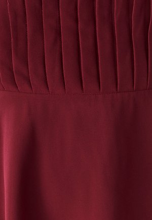 Robe bordeaux avec un corsage plissé texturé et une jupe lisse. Réalisée en un tissu doux avec une finition mate, présentant des détails de couture verticaux.